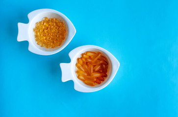 fish oil capsules in a white dish on a blue background
