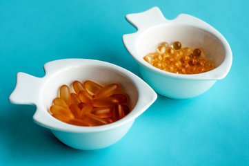 fish oil capsules in a white dish on a blue background