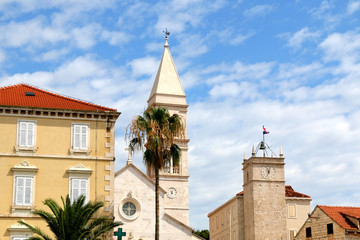 Obraz premium Historic parish Church of Mary's Annunciation and clock tower Leroj in Supetar, island Brac, Croatia.