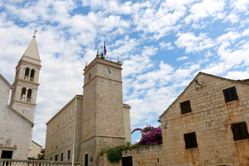 Fototapeta na wymiar Historic parish Church of Mary's Annunciation and clock tower Leroj in Supetar, island Brac, Croatia.