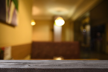 Image of grey wooden table in front of abstract blurred background of resturant cafe lights 