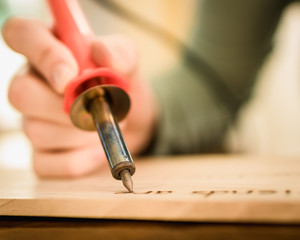 Person Holding a Wood Burning Tool, Burning Letters onto Wood