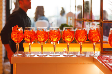 On the bar stand are glasses with orange cold drink. In glasses with a cocktail ice and oranges