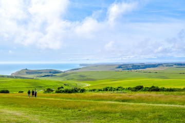 People walking through Sussex countryside with hills and the sea in summer