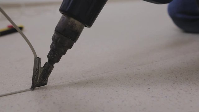Master welding machine type construction dryer solders two pieces of linoleum using a welding cord