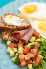 Close up of hotel breakfast with fried eggs, toasts with ham and cheese and summer salad