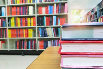 The old book on the wooden table in the library. Selective focus with blurred bookshelves background. Education and book's day concept.