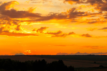 Fototapeta na wymiar Beautiful bright majestic dramatic evening sky at sunset orange color with rays. The sun shines over the horizon against the backdrop of thunderclouds at dusk