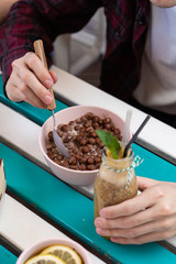 Man is having breakfast with green smoothie and chocolate cornflake balls on a terrace