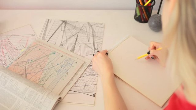Close up girl draws a pencil on paper at home. Female fashion designer drawing sketches the dress. Fashion designer drawing and paint. Stylish loft studio. Study design tutorial animator illustrator