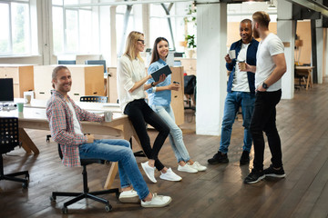 Young modern colleagues in smart casual wear working together while spending time in the creative office.