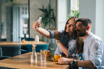 couple using cellphone while enjoying coffee in cafeteria