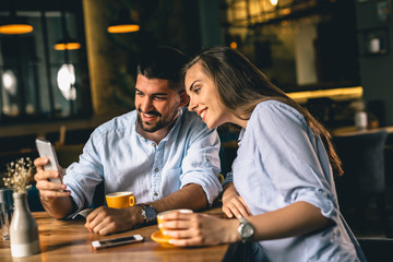 couple using cellphone while enjoying coffee in cafeteria