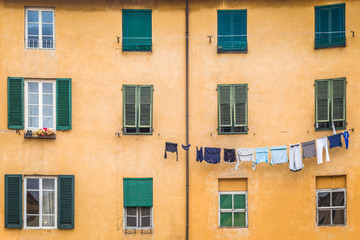 Fototapeta na wymiar Facade of an old house with hanging washed laundry in Lucca town, in an ancient city in the Tuscany region of Italy, Europe.
