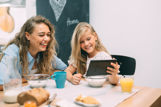 having a great time together. mother and daughter using tablet while having breakfast at home - Powered by Adobe