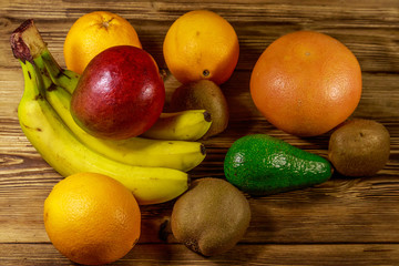 Assortment of tropical fruits on wooden table. Still life with bananas, mango, oranges, avocado, grapefruit and kiwi fruits