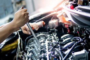 Male hand of auto mechanic fixing car engine with wrench in the garage. Automobile industry concept