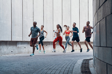Full length of people in sports clothing jogging while exercising outdoors