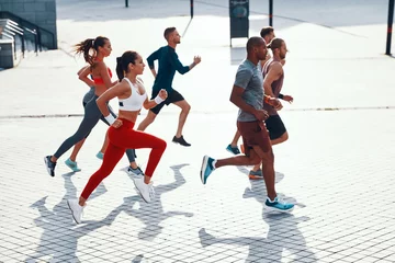 Keuken spatwand met foto Full length top view of people in sports clothing jogging while exercising on the sidewalk outdoors © gstockstudio