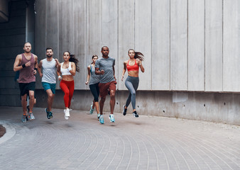 Full length of young people in sports clothing jogging while exercising outdoors