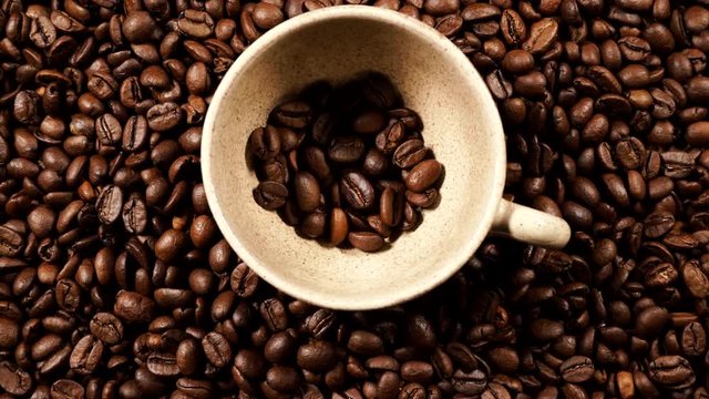 Coffee time. Small cup on roasted coffee beans background. Top view