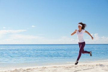 Young woman running on the beach. Summer concept. Healthy lifestyle. White sand, blue sky and crystal sea of tropical beach. Vacation at Paradise. Ocean beach relax, travel