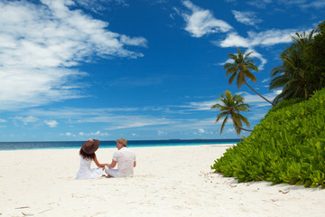 Fototapeta na wymiar Happy honeymoon vacation at summer. Couple relax on the white sand of beach. Happy sea lifestyle. Young family, man and woman rest on the beach of ocean. Couple in love travel to island. Love travel