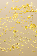 Festive golden stars of confetti are scattered on a light background.