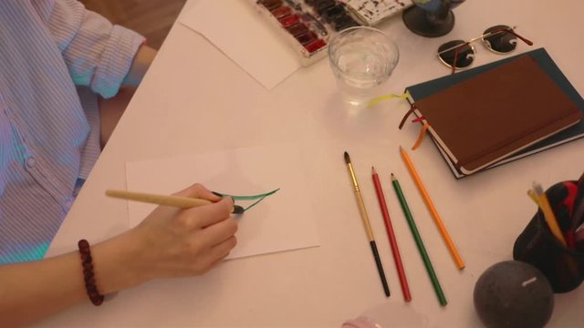 Close up shot of hand of artist's painting in watercolors using a paintbrush on watercolors paper. Study design tutorial animator illustrator work freelance session art fashion