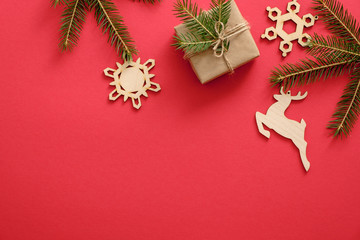 Handmade Christmas decorations and presents wrapped fir tree branches on red background. Flat lay, top view, copy space. Christmas, winter, New year concept. Greeting card template