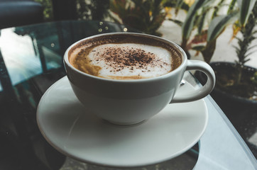 close up modern hot black coffee the cappuccino on dark background with coffee bubble foam pattern and texture in black cup looking and feel so delicious on glasses table in coffee shop.