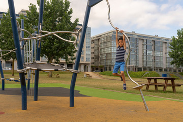 Child having fun on the playground in summer. Modern colorful park in sunny day. Children's fashion Children activities. Summer Vacation. Boy playing outdoors