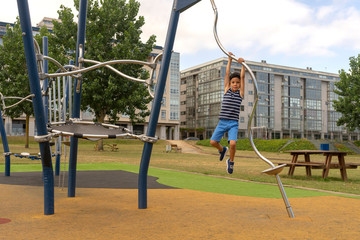 Child having fun on the playground in summer. Modern colorful park in sunny day. Children's fashion Children activities. Summer Vacation. Boy playing outdoors