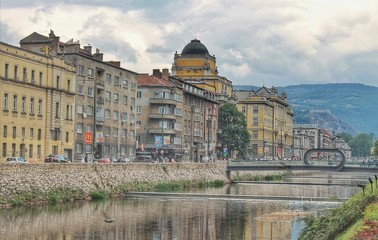 River view with old buildings, interesting brdige and mountains in Sarajevo