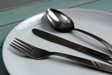 In a white plate are cutlery knife, fork, spoon