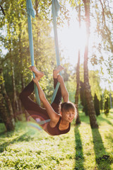Portrait of girl doing fly yoga at the tree outdoors. -  Image