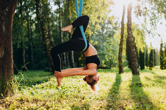 Young woman doing fly yoga at the tree hang upside down. Image