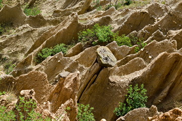 At close of the famous Stob Pyramids with unusual shape red and yellow rock formations, green bushes and trees around, west share of Rila mountain, Kyustendil region, Bulgaria, Europe 