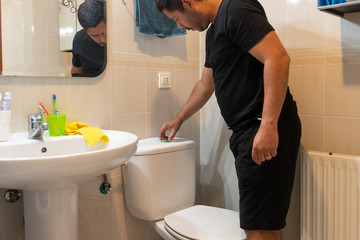 Man repairing toilet in the bathroom of his house