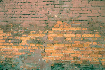 Background of old red brick. The wall of the old house without plaster. Brick is a durable material, but it collapses without a protective layer of plaster. Then the whole wall collapses.