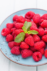 Fresh raspberries in a plate on a  vintage background.