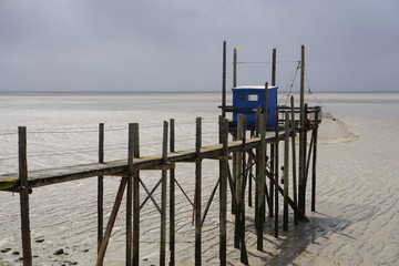 Fototapeta na wymiar old wooden fishing hut by the ocean at low tide in France