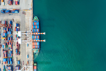 Aerial view. Container ship in pier with crane bridge carries out export and import business in the open sea. Logistics and transportation