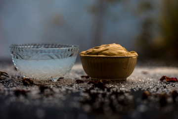 Obraz na płótnie Canvas Ubtan/face mask/face pack of Multani mitti or fuller's earth on wooden surface in a glass bowl consisting of Multani mitti and coconut oil for the remedy or treatment of suntan.On the wooden surface.