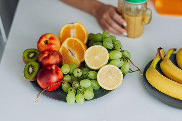 Image with fruit ingridients lying in the table. Female hand with glass of smoothie