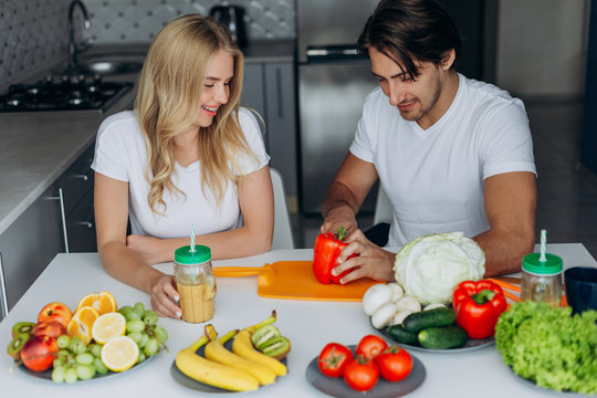 Couple in the kitchen sitting at the table with healthy food.- Image