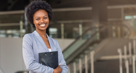 Beautiful Afro business woman holding a folder, looking at camera