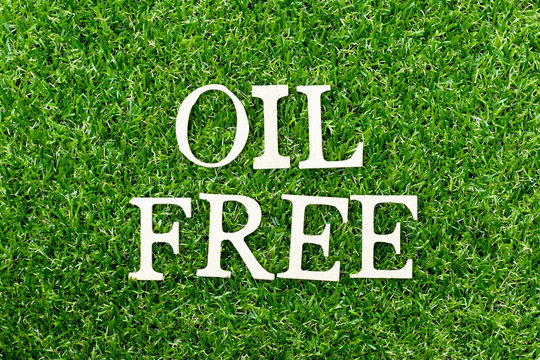 Wood alphabet letter in word oil freer on green grass background