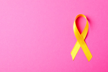 Yellow awareness ribbon on pink background, space for text