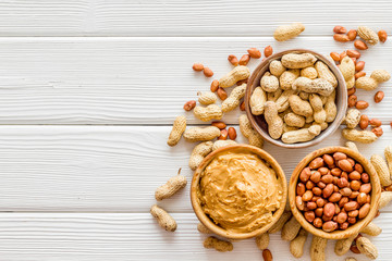 nuts in bowl for peanut butter for cooking breakfast at home on white wooden background top view mock-up